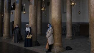 Mujeres posan para una foto junto a las columnas renovadas, durante una visita a la Iglesia de la Natividad en Belén, Cisjordania, el 16 de noviembre del 2021. 