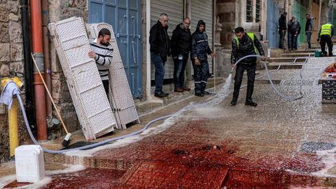 Trabajadores municipales lavan el suelo bañado de sangre tras el ataque en la Ciudad Vieja de Jerusalem.