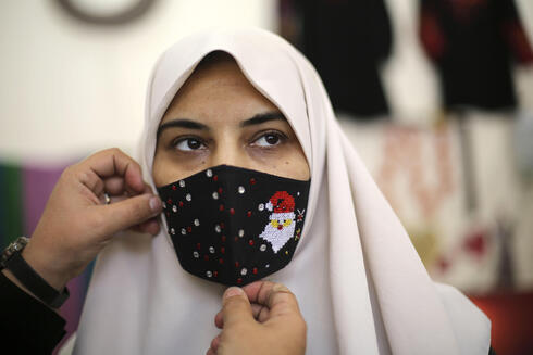 Una mujer palestina prueba una máscara con temática navideña en la ciudad de Gaza. 