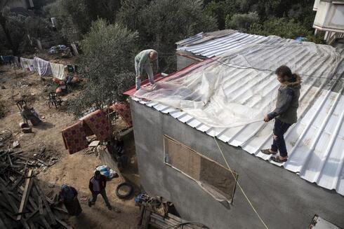 Palestinos cubren el techo de su casa con nylon para protegerla de las goteras provocadas por la lluvia, en una localidad del norte de la Franja de Gaza.  