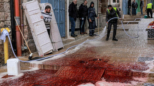 Trabajadores municipales lavan la sangre en el lugar de un fatal ataque terrorista afiliado a Hamás en Jerusalem, el 21 de noviembre de 2021.