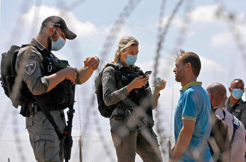 Fuerzas israelíes interrogan a palestinos en un cruce en la frontera con Cisjordania.  