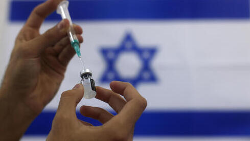 Una dosis de vacuna contra el COVID-19. De fondo, la bandera israelí. 