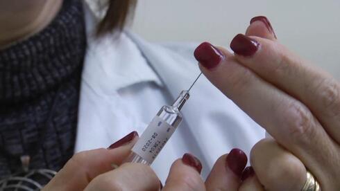 Trabajadora de la salud se apresta a vacunar contra la gripe. 