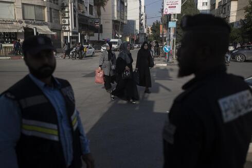 Mujeres palestinas caminan cerca de policías de Hamás en la ciudad de Gaza.