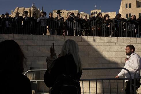 Judíos ultraortodoxos observan cómo una integrante de Mujeres del Muro lleva un rollo de la Torá. 
