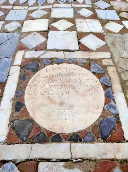 La placa con una inscripción en griego, la palabra "shalom" en letras hebras y una menorá, hallada en el centro de la sinagoga. (Demirören Haber Ajansı/Universidad de Anatolia) La placa con una inscripción en griego, la palabra "shalom" en letras hebras y una menorá hallada en el centro de la sinagoga.