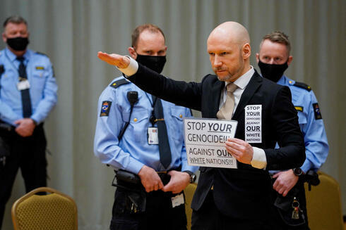 Anders Behring Breivik hace el saludo nazi en la corte durante la audiencia  de libertad condicional. "Detengan su genocidio contra nuestras naciones blancas", dice el cartel. 