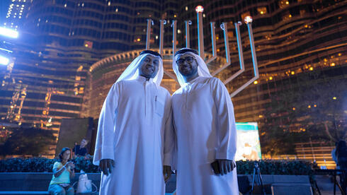 Dos residentes locales de los Emiratos Árabes Unidos frente a una menorá. 