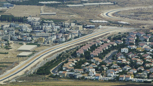 Vista aérea muestra una aldea palestina, a la izquierda, y un asentamiento, a la derecha, separados por el muro de separación en Cisjordania.
