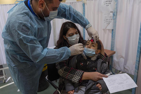 Un trabajador sanitario toma una muestra de hisopo nasal de un niño palestino en un centro de pruebas COVID-19, en la ciudad cisjordana de Ramallah. (AP) Un trabajador sanitario toma una muestra de hisopo nasal de un niño palestino en un centro de pruebas COVID-19, en la ciudad cisjordana de Ramallah