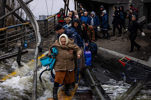 Civiles ucranianos saltan sobre un puente derrumbado mientras son evacuados en Irpin en medio de la ofensiva rusa. (AFP) Civiles ucranianos saltan sobre un puente derrumbado mientras son evacuados en Irpin en medio de la ofensiva rusa.