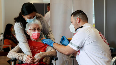 Anciana recibe una vacuna de refuerzo. 