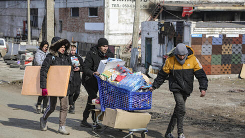 Personas recogiendo agua y alimentos en la ciudad de Mariupol.