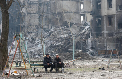 Civiles sentados entre los escombros, en Mariupol, Ucrania.