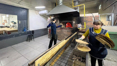 Un trabajador de una fábrica hace matzá de shmurah bajo supervisión en Ucrania.  