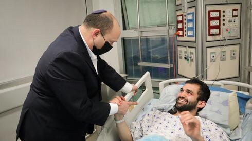 El primer ministro Naftalí Bennett visita a uno de los heridos en el ataque terrorista del jueves en Tel Aviv. 