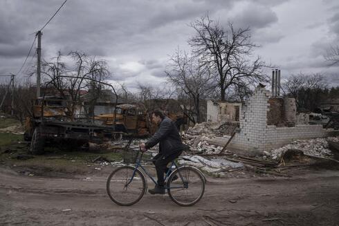 Un hombre pasa en su bicicleta en medio de la destrucción de una ciudad ucraniana. (AP) Guerra en Ucrania