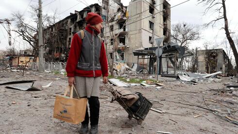 Una mujer camina entre los escombros que quedaron de Mariupol, asediada por bombardeos rusos.