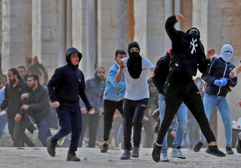 Manifestantes palestinos lanzando piedras contra las fuerzas israelíes en el recinto de la mezquita de al-Aqsa. 