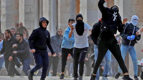 Palestinos arrojan piedras a la policía en el complejo de la mezquita de Al Aqsa durante los disturbios del 2021. (AFP) Palestinos arrojan piedras a la policía en el complejo de la mezquita de Al Aqsa a principios de este mes.
