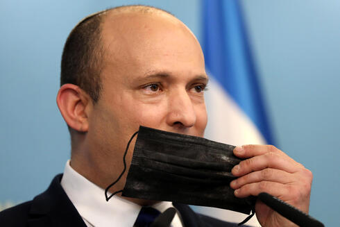 El primer ministro Naftalí Bennett sostiene una máscara facial durante una conferencia de prensa sobre la situación de COVID-19 en Israel. (EPA) El primer ministro Naftalí Bennett sostiene una máscara facial durante una conferencia de prensa sobre la situación de COVID-19 en Israel.