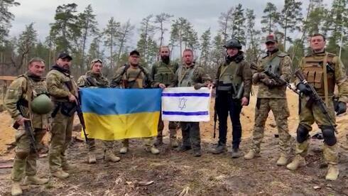 Voluntarios israelíes en el ejército ucraniano sostienen las banderas israelí y ucraniana. 