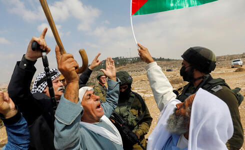 Manifestantes palestinos gesticulan junto a las fuerzas israelíes durante una protesta contra los asentamientos israelíes en Masafer Yatta, en Cisjordania, el 2 de octubre de 2021. (Reuters) Manifestantes palestinos gesticulan junto a las fuerzas israelíes durante una protesta contra los asentamientos israelíes en Masafer Yatta, en Cisjordania, el 2 de octubre de 2021.