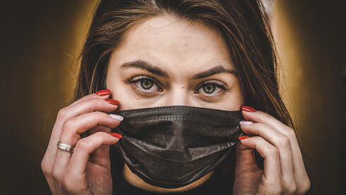 Una mujer usa una máscara para protegerse de COVID-19. 