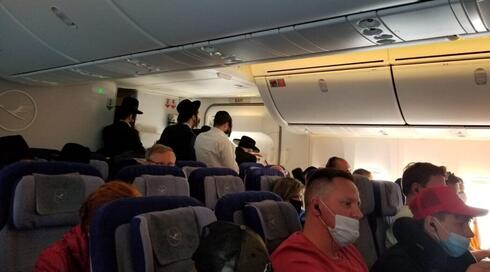 En el interior del vuelo de Lufthansa a Frankfurt, hombres judíos ortodoxos rezan en la parte trasera del avión. 