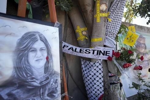 La cinta amarilla marca los agujeros de bala, y un retrato y flores crean un monumento improvisado en el sitio donde fue asesinada la periodista Shireen Abu Akleh. (AP) La cinta amarilla marca los agujeros de bala, y un retrato y flores crean un monumento improvisado en el sitio donde fue asesinada la periodista Shireen Abu Akleh.