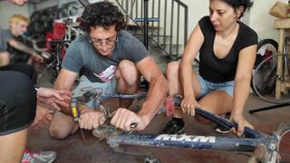 Nathanael Singer les muestra a los visitantes del taller cómo arreglar una bicicleta.