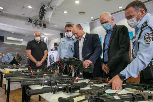 El primer ministro Naftali Bennett, el ministro de Seguridad Pública Omer Barlev y el comisario de policía Kobi Shabtai examinan las armas de fuego incautadas en el sector árabe. 