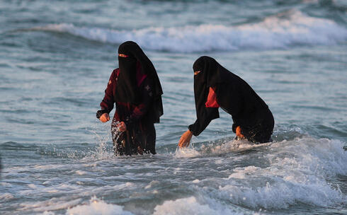 Mujeres de Gaza disfrutan de las olas en la orilla del mar.