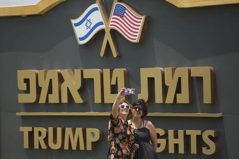 Dos mujeres se hacen una foto contra un cartel a la entrada de Trump Heights.
