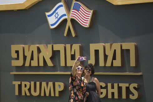 Dos mujeres se hacen una foto contra un cartel a la entrada de Trump Heights. (Gettyimages) Dos mujeres se hacen una foto contra un cartel a la entrada de Trump Heights.