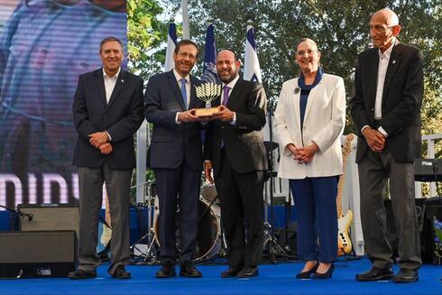 El presidente Isaac Herzog y la primera dama Michal Herzog flanqueados por los ganadores del Premio Presidencial al Voluntariado 2022.