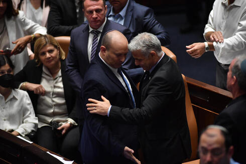 Bennett intercambia asientos con Lapid tras la votación que disolvió la 24° Knesset de Israel. 