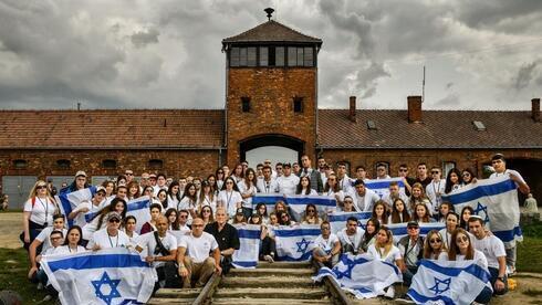 Estudiantes vestidos con la bandera israelí en Auschwitz durante un viaje de estudios sobre el Holocausto a Polonia.