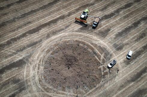 Un agricultor recoge la cosecha en un campo alrededor de un cráter dejado por un cohete ruso a diez kilómetros de la línea del frente en la región de Dnipropetrovsk, Ucrania, el 4 de julio de 2022. 