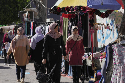 Mujeres caminan por una calle comercial en Gaza. 
