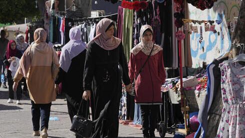 Mujeres caminan por una calle comercial en Gaza. 