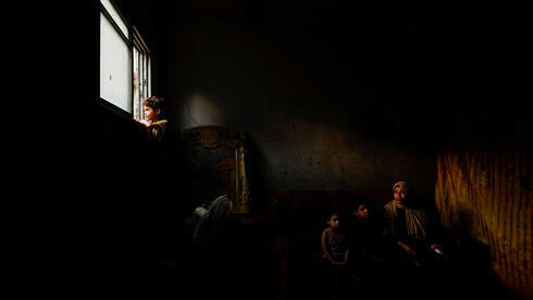 Una familia palestina sentada en su casa en medio de largos cortes de electricidad.