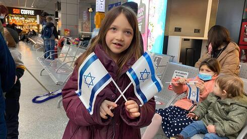 Una niña inmigrante ucraniana sostiene banderas israelíes al llegar al aeropuerto de Tel Aviv. 