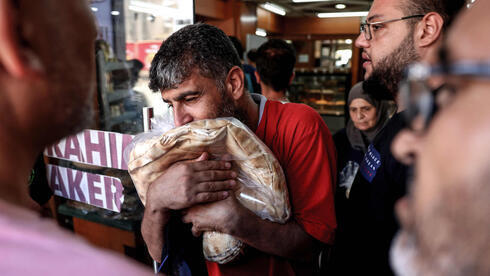 Un hombre sosteniendo una bolsa de pan de pita en una panadería, en Beirut, Líbano. 