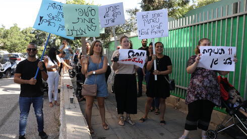 Padres afuera del jardín de infantes en Holon con carteles de protesta