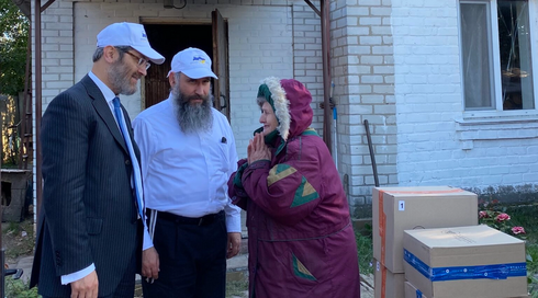 Los rabinos Raphael Rotman, a la izquierda, y Meir Stambler, ambos de la Federación de Comunidades Judías de Ucrania, entregan cajas a una anciana ucraniana no judía en Bucha que recibe su ayuda desde hace meses