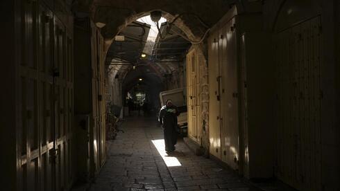 Una mujer pasa por delante de las tiendas cerradas en la Ciudad Vieja de Jerusalem.