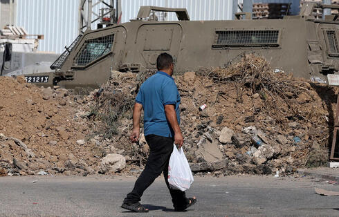 Un hombre camina junto a un vehículo blindado de las FDI después de que Israel bloqueara las entradas a Naplusa
