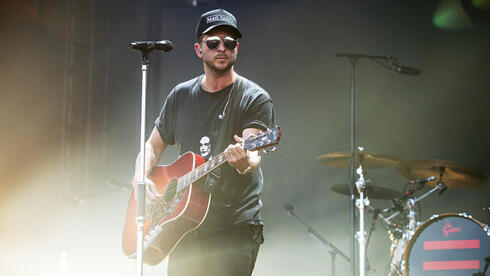 El cantante Ryan Tedder con su guitarra en el escenario. . 